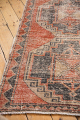 Distressed Oushak rug detail with faded brick red, charcoal, beige geometric patterns.