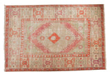 Vintage distressed Oushak carpet with a diamond medallion in blush, tangerine, and soft seafoam green.