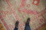 A worn vintage Oushak carpet corner with raspberry red, seafoam green, and ivory geometric motifs.