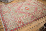 Vintage distressed Oushak carpet with time-softened blush, seafoam, and ivory tones, viewed from an angle.