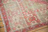 Worn pile on a vintage Oushak carpet corner with a raspberry red border and ivory hook and latch motifs.