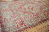 Angled view of a distressed Oushak carpet showing its soft, low pile and wide geometric border.