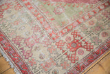 Corner of a distressed Oushak carpet showing hook motifs in ivory, blush, and seafoam green.