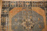 Distressed Oushak runner detail: charcoal geometric medallion, pale rust field, visible foundation.