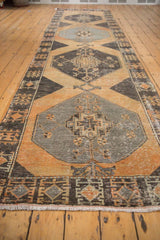 Distressed charcoal geometric border and secured fringe of the vintage Oushak runner.