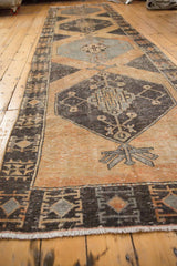 Distressed Oushak runner end showing worn pale rust and charcoal brown motifs, fringed.