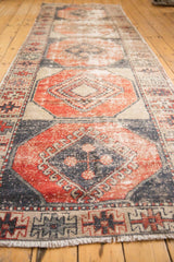 Distressed Oushak runner's worn texture, brick cherry red and navy charcoal geometric guls, with fringe.