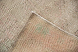 Distressed Oushak rug corner showing worn pile, underlying foundation, and secured edge.