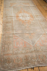 Distressed vintage Oushak runner end, muted peach and silver geometric pattern, with fringe.