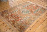 Distressed hand-knotted rug showing madder rust, sky blue, ivory, and geometric patterns.