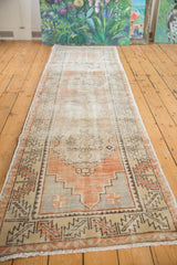 Lower corner of a distressed Oushak rug runner showing apricot, ivory, and blue stepped spandrels.