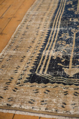 Distressed Oushak rug detail with prominent wear, dark navy blue, beige, and geometric border.