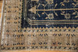 Distressed vintage Oushak rug corner with visible wear, fringe, navy and beige border.