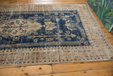 Distressed Oushak carpet, navy blue and antique ivory border with visible texture and wear.