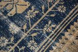 Distressed vintage Oushak rug showing worn navy blue pile and ivory floral motifs.
