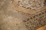Worn pile texture on a distressed Oushak rug, showing geometric patterns in beige and slate.