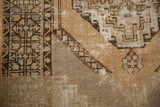 Section of vintage Oushak rug showing distressed pile, pale apricot, antique ivory, and charcoal geometric patterns.