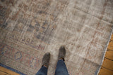 Distressed Oushak carpet showing worn texture, abrash, and visible foundation in pale rust and blue.