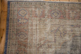 Worn pile and visible foundation on a distressed Oushak rug corner in rust and blue tones.