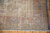 Distressed vintage Oushak rug corner displaying worn texture, pale rust, ivory, and denim blue.
