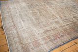 Worn Oushak rug corner showing visible foundation, pale rust border, and denim blue edge.