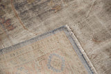 Distressed Oushak carpet corner, revealing worn pile texture, exposed foundation, and secured edge.