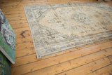 Faded Rococo-stylized floral arrangements and distressed pale beige Oushak field.