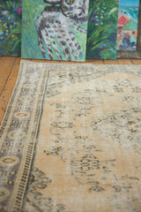 Pale beige vintage Oushak rug section, featuring distressed Rococo stylized floral motifs.