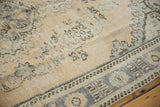 Distressed Oushak carpet texture, showing faded pale blue Rococo floral motifs and worn knot heads.