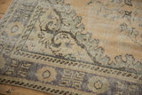 Distressed vintage Oushak carpet detail with faded curvilinear Rococo pattern and worn texture.