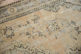 Distressed Oushak rug detail with worn pile, faded beige, pale blue, and brown floral patterns.