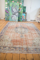 Decorative distressed texture and worn fringe on a vintage Oushak rug, showing rust and navy tones.