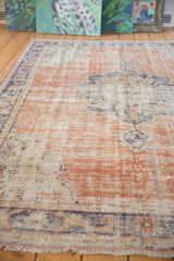 Distressed Oushak carpet texture with abrashed terra cotta, navy, ivory, and visible foundation.