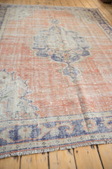 Fringe and distressed texture of a vintage Oushak rug in rust and navy.