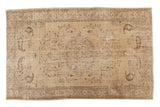Distressed Oushak carpet featuring a faded scalloped medallion, vinery, and muted beige tones.