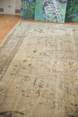Distressed vintage Oushak carpet with faded vinery motifs and visible worn knot heads.
