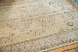 Distressed Oushak carpet detail with faded vinery, boteh motifs, and worn texture in ivory, beige, mauve.