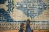 Visible distressed texture of a vintage Oushak carpet, showing worn blue patterns and detailed border.