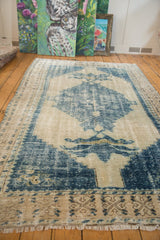 Distressed blue and ivory vintage Oushak carpet showing serrated medallion and worn pile.