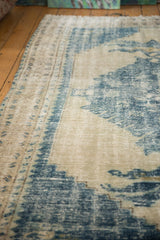Distressed Oushak rug detail showing textured worn pile, faded ivory, and denim blue palette.