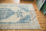 Worn cobalt blue design on distressed Oushak carpet with ivory field and geometric border.