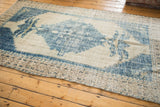Distressed beige and blue border pattern of a vintage Oushak carpet corner.