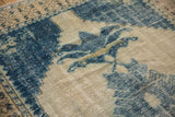 Distressed vintage Oushak carpet featuring worn ivory and serrated denim blue floral palmette.