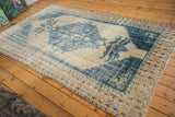 Distressed vintage Oushak carpet with ivory field and faded blue floral palmette design.