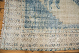 Distressed vintage Oushak rug corner, showing faded cobalt blue serrated pattern edge and ivory fringe.
