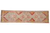 Distressed vintage Oushak runner with faded geometric medallions in rust, saffron, and pale blush.