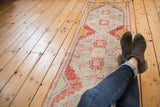 Distressed vintage Oushak rug close-up, brick rust and pale rose geometric motifs, even wear.
