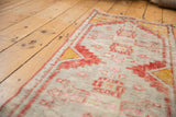 Distressed Oushak rug corner, geometric patterns in brick rust, saffron, pale rose.