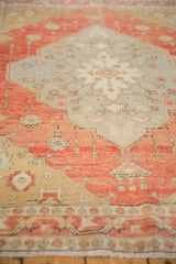 Vintage distressed Oushak rug's terra cotta, beige border, aged pile, and fringed end.