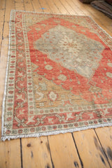 Distressed vintage Oushak rug with worn pile, terra cotta border, and beige fringe.